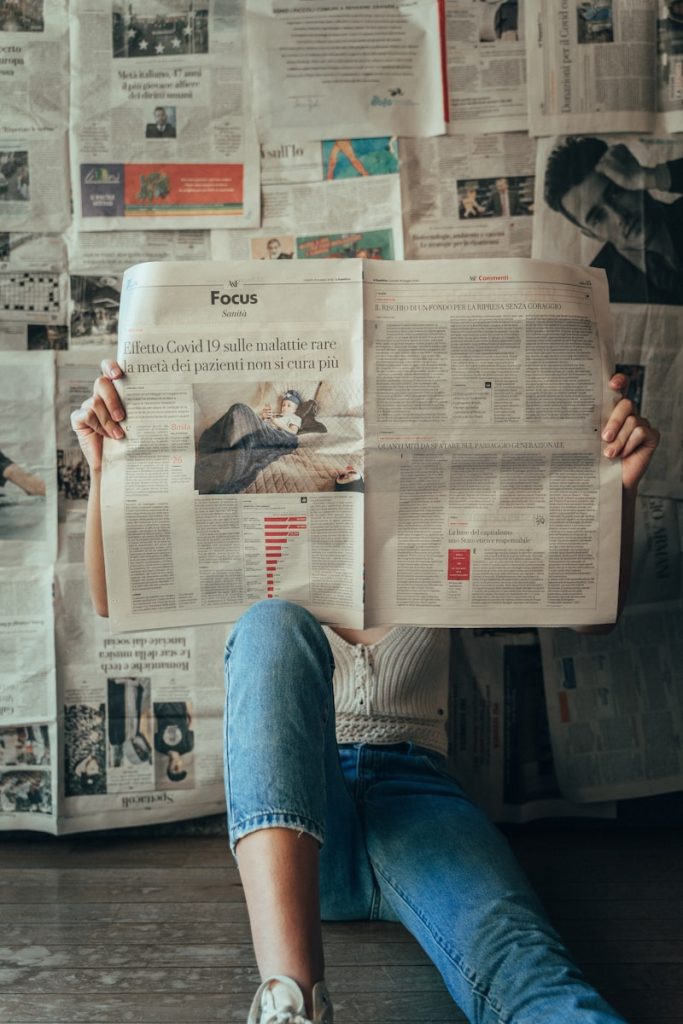 Photo by Ludovica Dri person in blue denim jeans holding white magazine